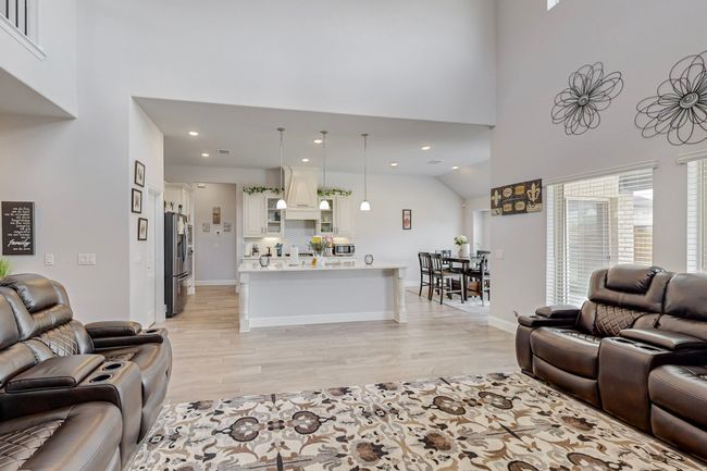 Living room featuring light wood-style flooring, a towering ceiling, baseboards, and recessed lighting | Image 6