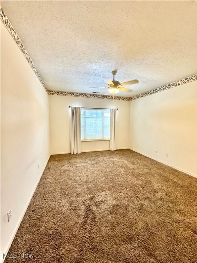 Carpeted spare room with ceiling fan and a textured ceiling | Image 21