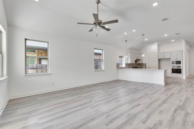 Unfurnished living room featuring lofted ceiling, recessed lighting, light wood finished floors, and a ceiling fan | Image 7