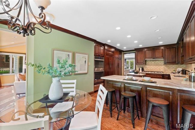Kitchen with crown molding, stainless steel double oven, recessed lighting, light wood finished floors, and backsplash | Image 16