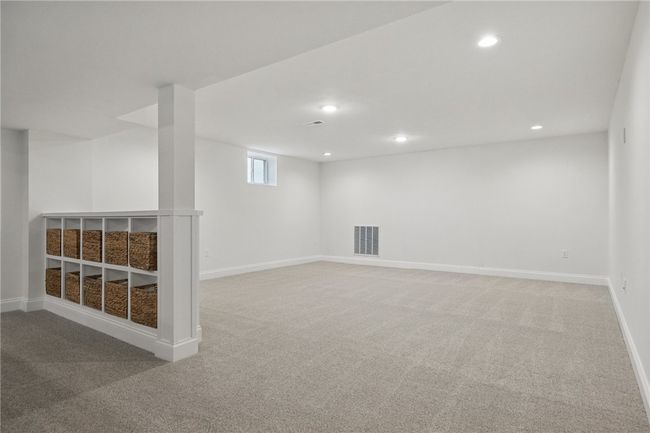 Expansive finished basement offering a versatile layout perfect for a media room, playroom, billiard room or entertaining space. Features recessed lighting, plush carpeting, and neutral tones throughout—complete with a walk-out door for easy outdoor access to covered lower level patio and added convenience. | Image 30
