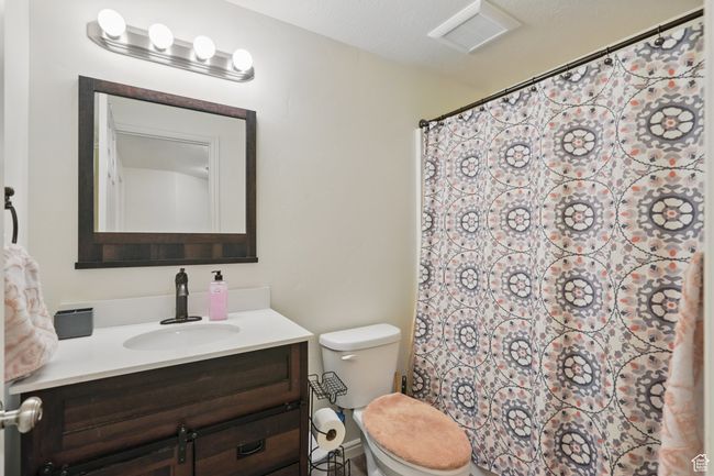 Bathroom with a shower with shower curtain, vanity, visible vents, and toilet | Image 41