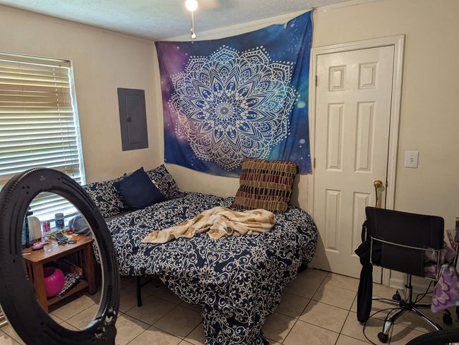 Bedroom featuring electric panel, light tile patterned floors, and a textured ceiling | Image 6