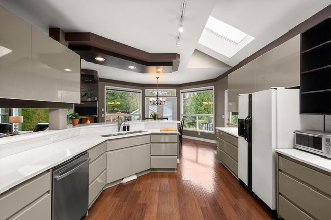 Kitchen featuring dark wood finished floors, dishwasher, light countertops, a peninsula, and open shelves | Image 13