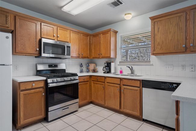 Kitchen with a sink, visible vents, light countertops, appliances with stainless steel finishes, and decorative backsplash | Image 9