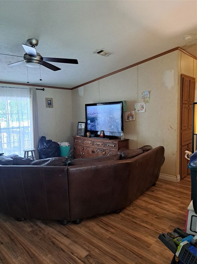 Living room with dark wood-style floors, crown molding, and a ceiling fan | Image 4