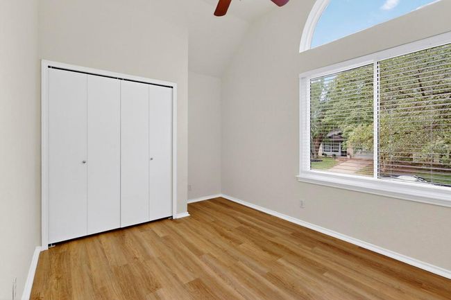 Unfurnished bedroom featuring light wood-type flooring, lofted ceiling, baseboards, a closet, and ceiling fan | Image 25