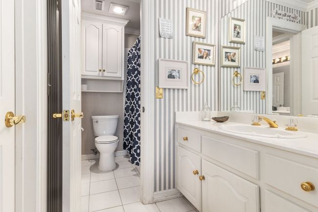 Full bath featuring vanity, tile patterned flooring, toilet, and wallpapered walls | Image 25