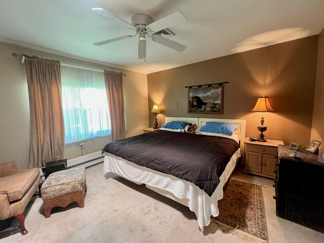 Bedroom featuring a baseboard heating unit, ceiling fan, and light colored carpet | Image 11