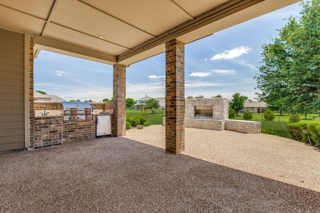 Outdoor living/kitchen featuring exterior fireplace, grill and a sink | Image 31
