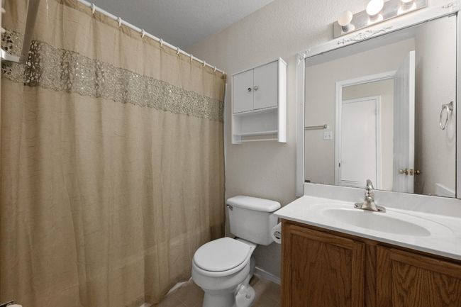 Bathroom with toilet, vanity, a shower with shower curtain, and tile patterned floors | Image 22