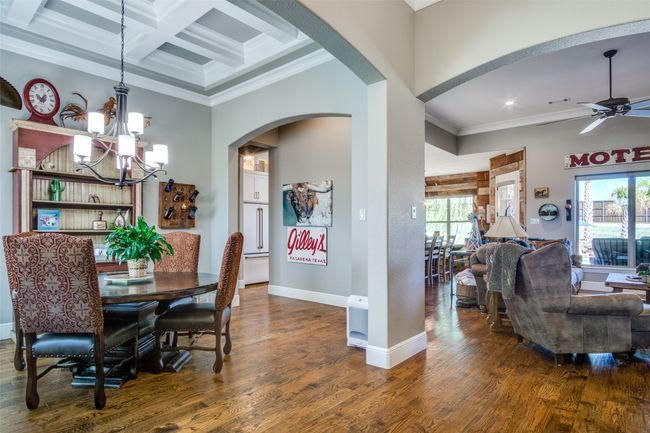 Dining space featuring coffered ceiling, a healthy amount of sunlight, ornamental molding, arched walkways, and wood finished floors | Image 5
