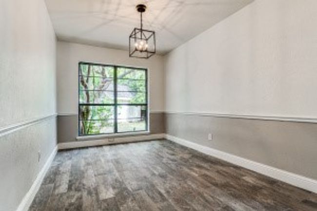 Spare room featuring baseboards, a notable chandelier, and wood finished floors | Image 11