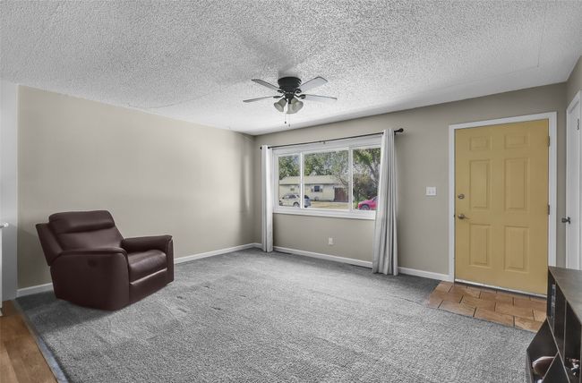 Living area featuring ceiling fan, carpet flooring, a textured ceiling, and baseboards | Image 8