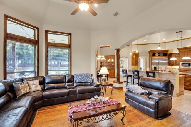Living area with arched walkways, ceiling fan, light wood finished floors, and decorative columns | Image 17
