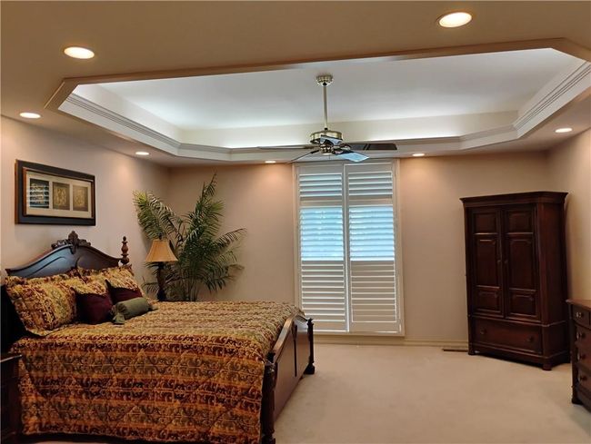 Bedroom featuring light colored carpet, ceiling fan, recessed lighting, and a raised ceiling | Image 43
