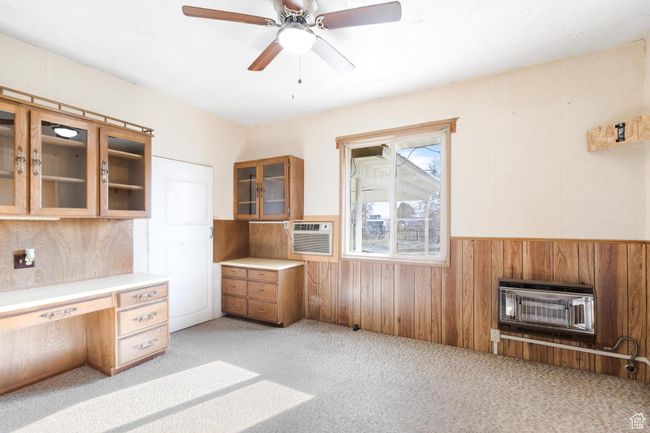 Unfurnished office with wooden walls, heating unit, a ceiling fan, light carpet, and wainscoting | Image 22