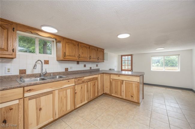 Kitchen with a sink, a peninsula, light tile patterned floors, a textured ceiling, and baseboards | Image 17