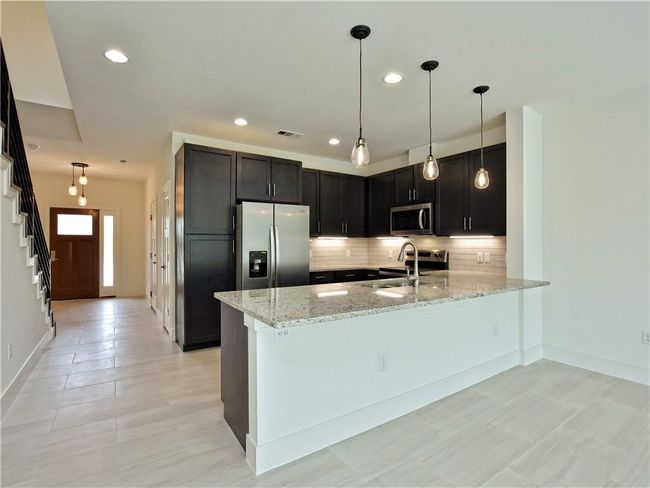 Kitchen featuring stainless steel appliances, light stone counters, backsplash, a peninsula, and recessed lighting | Image 10