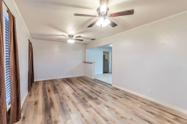Spare room with baseboards, crown molding, a ceiling fan, and wood finished floors | Image 5