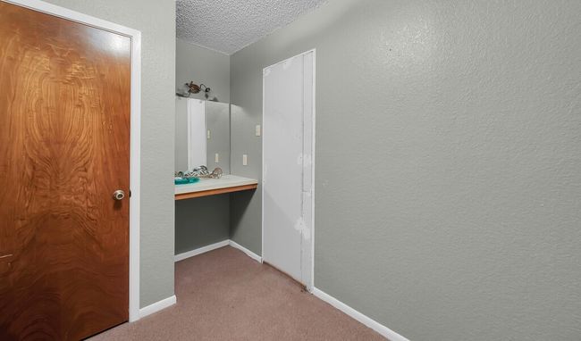 Bathroom featuring a textured ceiling, baseboards, and a sink | Image 6