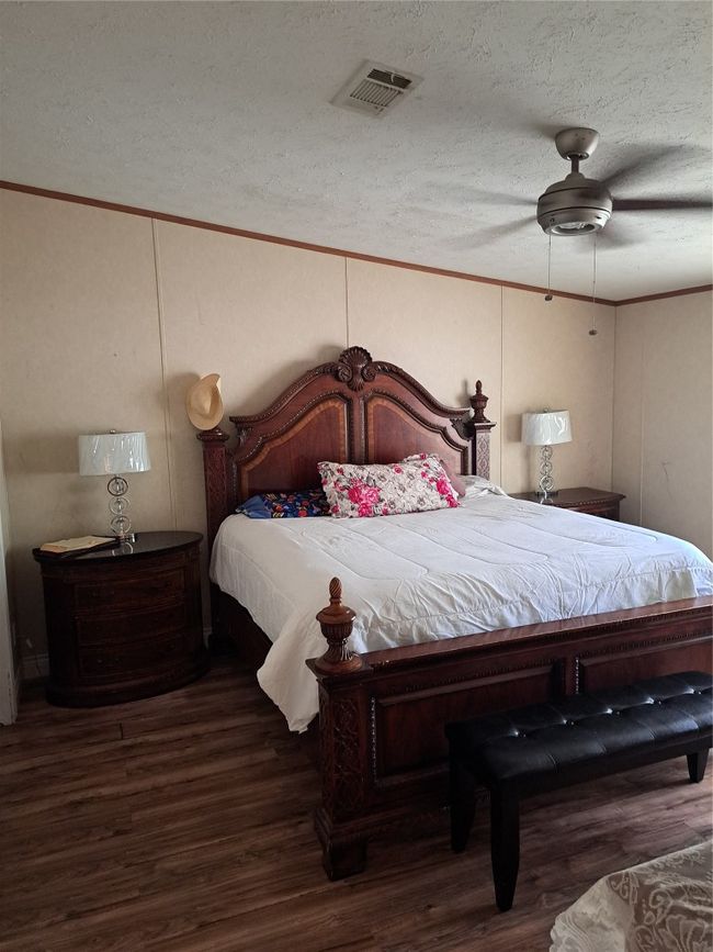 Bedroom featuring wood finished floors, a textured ceiling, a ceiling fan, and ornamental molding | Image 8