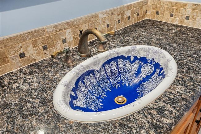 CUSTOM SINK IS S TRUE FOCAL POINT, LUXURIOUS GRANITE COUNTER TOPS FRAMED WITH A TILE BORDER AND BRASS FIXTURE | Image 28
