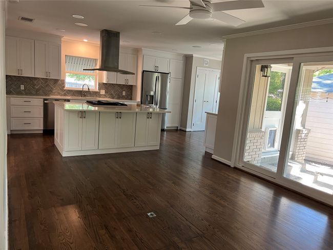 Kitchen featuring white cabinets, ventilation hood, dark wood-style flooring, stainless steel appliances, and tasteful backsplash | Image 8