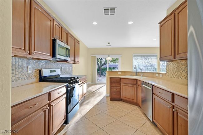 Kitchen featuring a sink, tile backsplash, stainless steel appliances, and light countertops | Image 9
