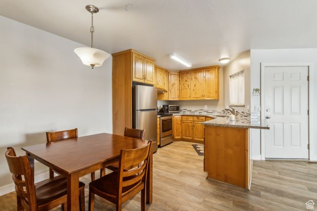 Kitchen featuring stainless steel appliances, a peninsula, a sink, light wood finished floors, and pendant lighting | Image 5