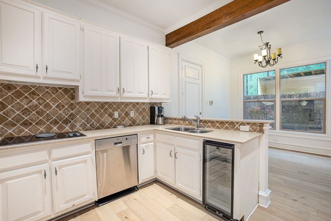 Kitchen with an inviting chandelier, a sink, beam ceiling, stainless steel dishwasher, and beverage cooler | Image 8