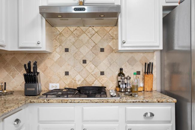 Kitchen featuring stainless steel appliances, exhaust hood, white cabinets, and backsplash | Image 17
