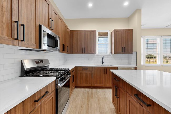 Kitchen featuring appliances with stainless steel finishes, light wood-style floors, backsplash, brown cabinetry, and recessed lighting | Image 15