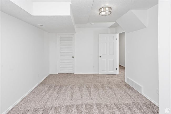 Empty room featuring baseboards, a textured ceiling, visible vents, and carpet | Image 31