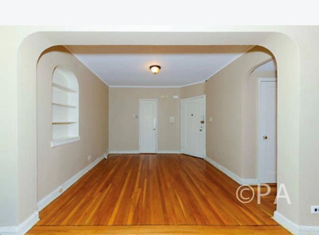 Empty room with built in shelves, baseboards, and wood finished floors | Image 8