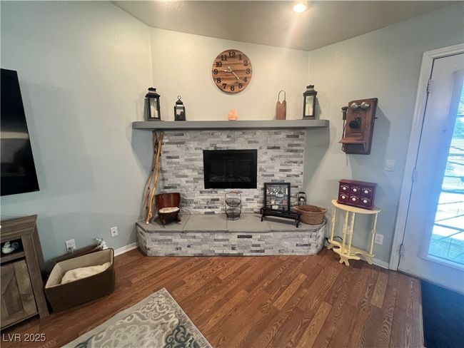Living room with a stone fireplace and wood finished floors | Image 8