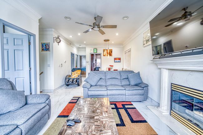 Living room with a ceiling fan, recessed lighting, ornamental molding, a fireplace, and marble finish floors | Image 6