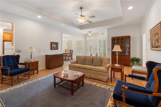 Living area featuring light wood-type flooring, a ceiling fan, ornamental molding, and a raised ceiling | Image 30