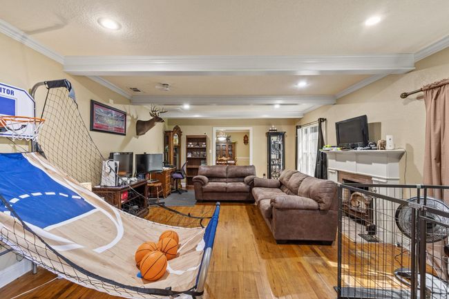 Living room with visible vents, wood-type flooring, beamed ceiling, crown molding, and a fireplace | Image 16