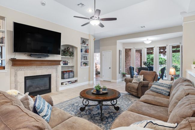 Great room featuring stone tile floors, built in shelves, fireplace, and recessed lighting | Image 7
