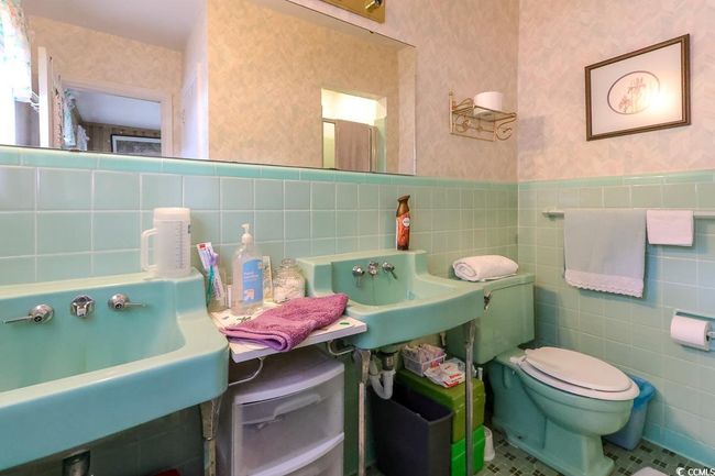 Bathroom featuring wallpapered walls, tile walls, toilet, a sink, and wainscoting | Image 19