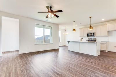 Kitchen featuring tasteful backsplash, hardwood / wood-style flooring, stainless steel appliances, ceiling fan with notable chandelier, and an island with sink | Image 3