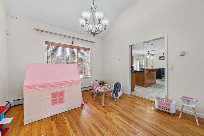 Game room featuring baseboards, an inviting chandelier, lofted ceiling, light wood finished floors, and a baseboard radiator | Image 15