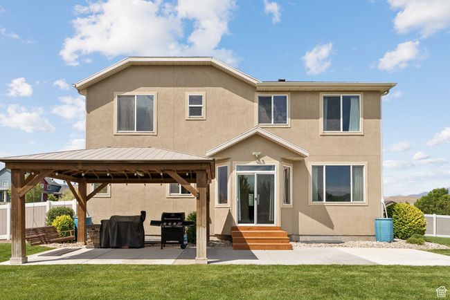 Rear view of property featuring entry steps, a gazebo, stucco siding, a standing seam roof, and a patio | Image 43