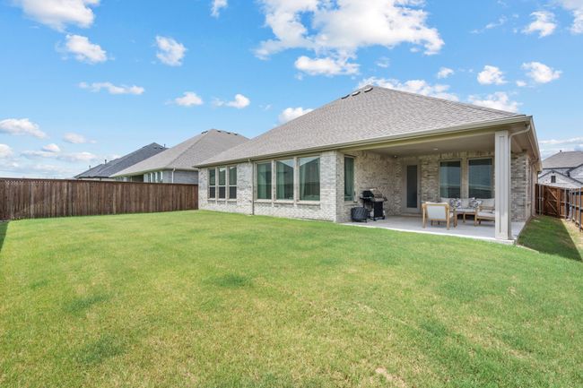Back of property featuring a fenced backyard, a patio area, brick siding, roof with shingles, and outdoor lounge area | Image 31