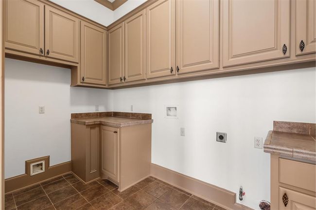 This photo showcases a spacious laundry room with ample cabinetry for storage providing a functional and organized space. | Image 25