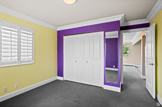 Unfurnished bedroom featuring ornamental molding, a closet, and dark colored carpet | Image 25