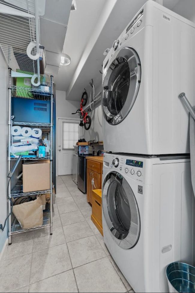 Laundry area featuring estacked washer and dryer and light tile patterned floors | Image 25