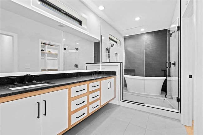 Bathroom with double vanity, a freestanding tub, a stall shower, tile patterned flooring, and recessed lighting | Image 20