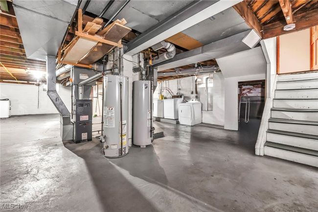 Unfinished below grade area with stairway, washer and dryer, heating unit, and gas water heater | Image 19